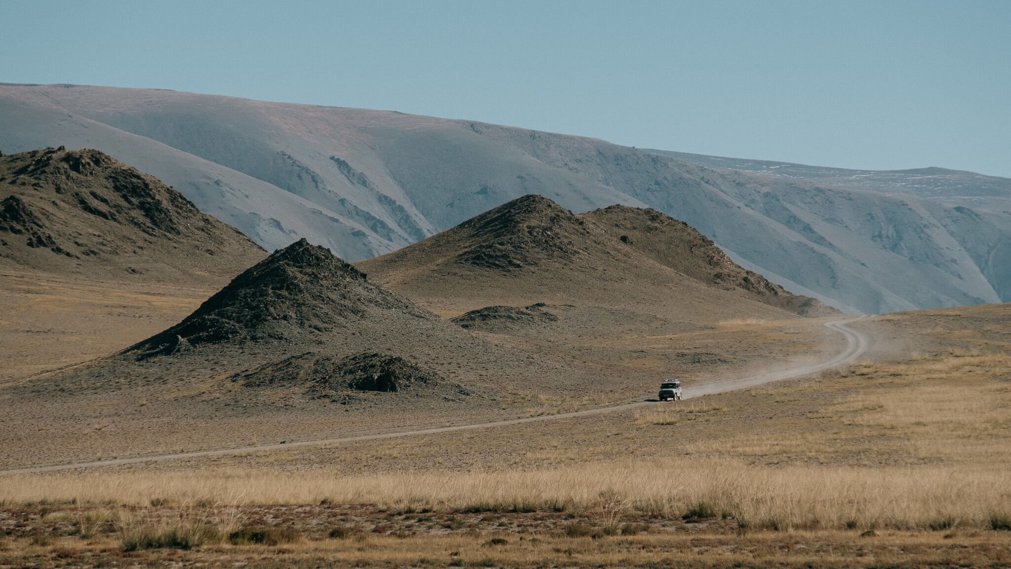 A lone road curving past a conical hill