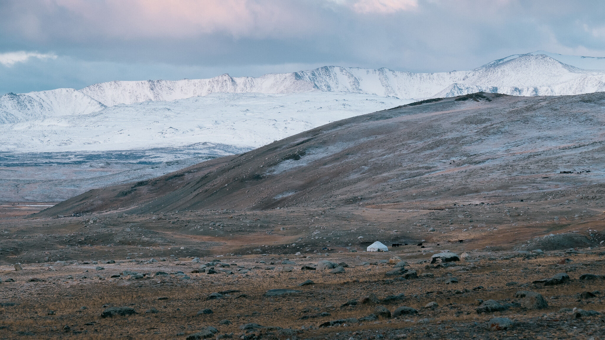 A snow-covered ridgeline under a storm sky in the Altai
